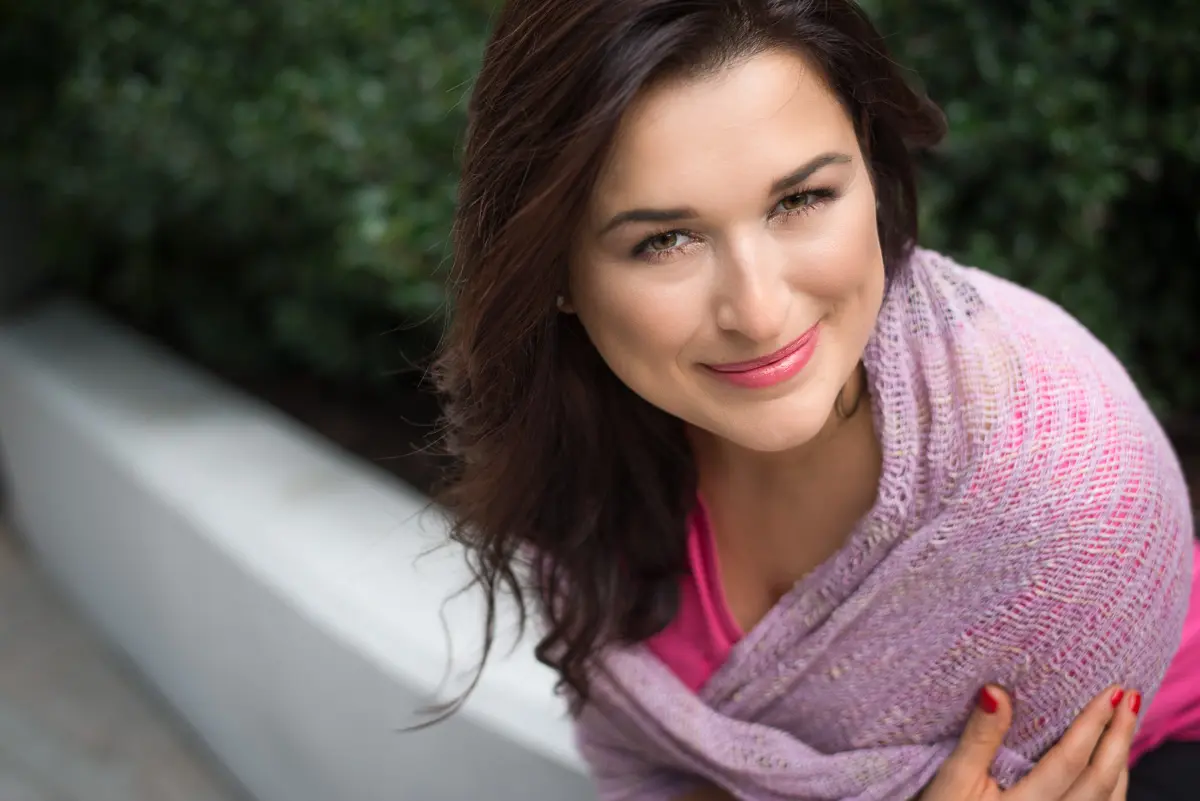 Paulina Drzewień uśmiecha się, siedząc w naturalnym otoczeniu.